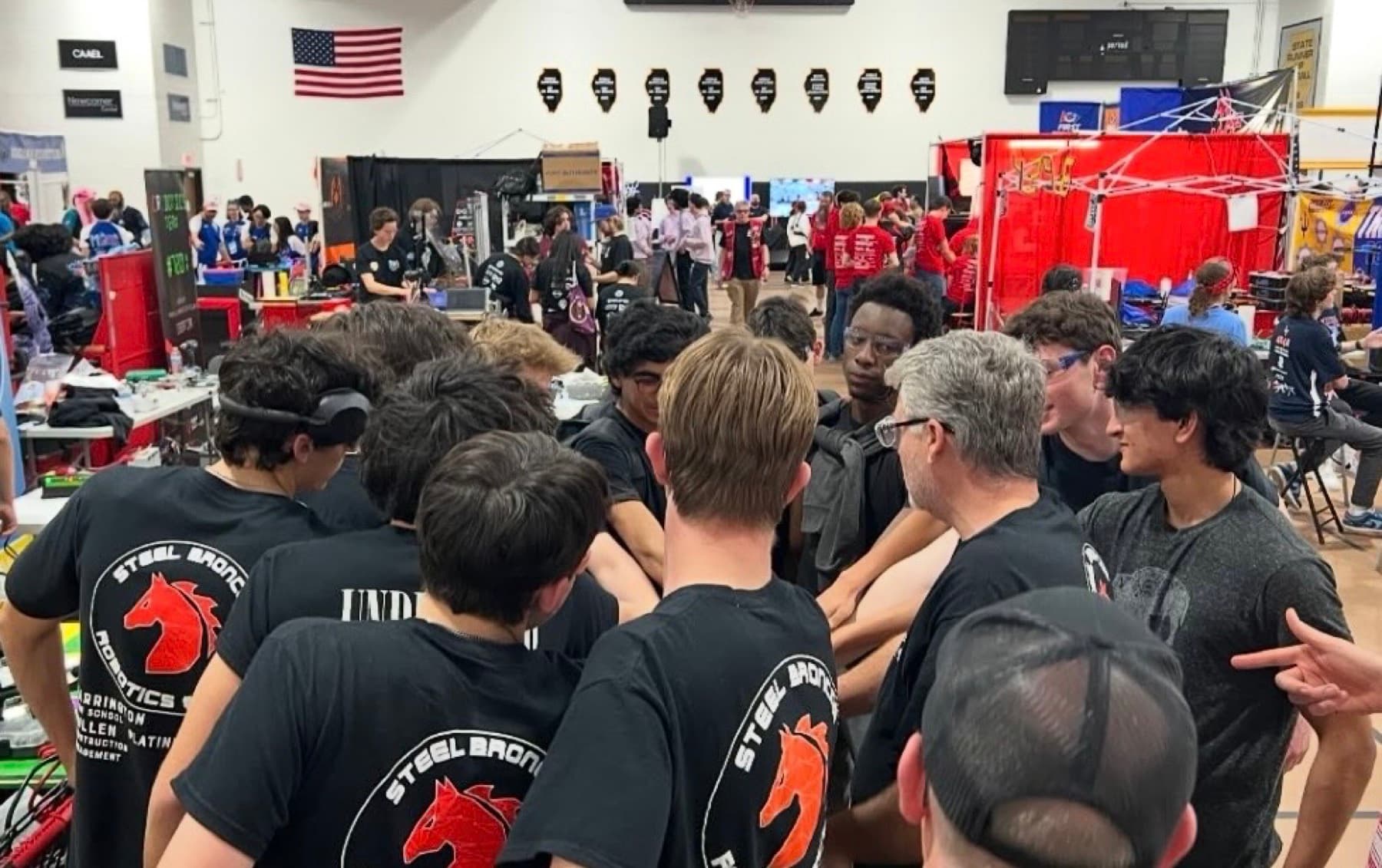 The team huddled together in the pit, hands in the centre, before a match